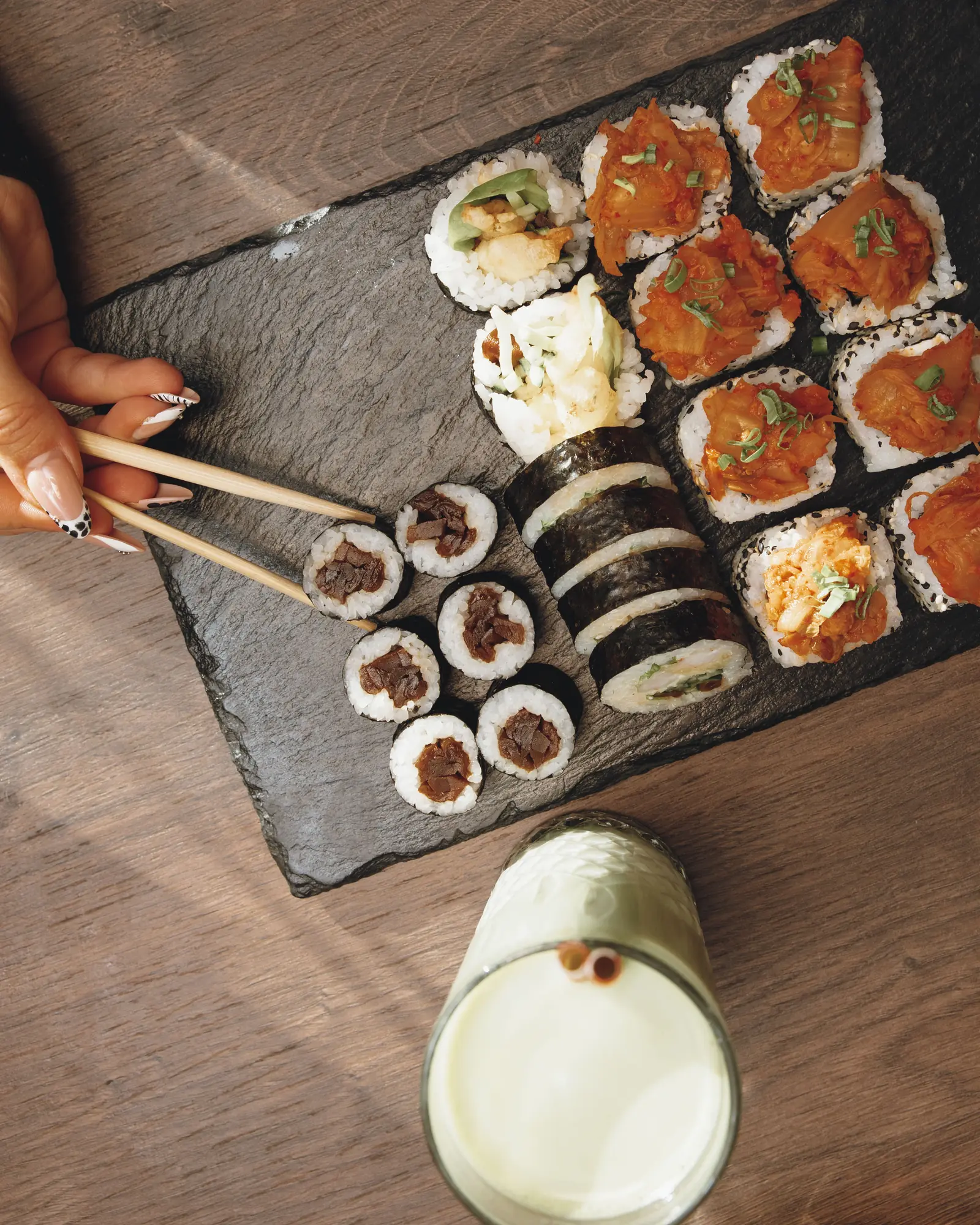 Sushi na kamiennej desce i koktajl na drewnianym stole